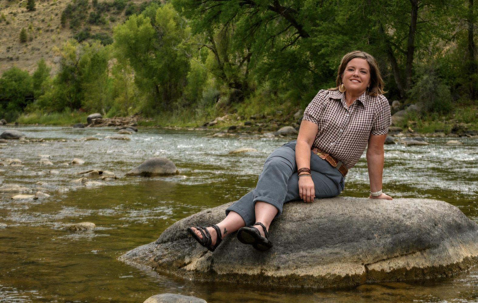 Jodie Miller sitting on a rock in the middle of the Animas river