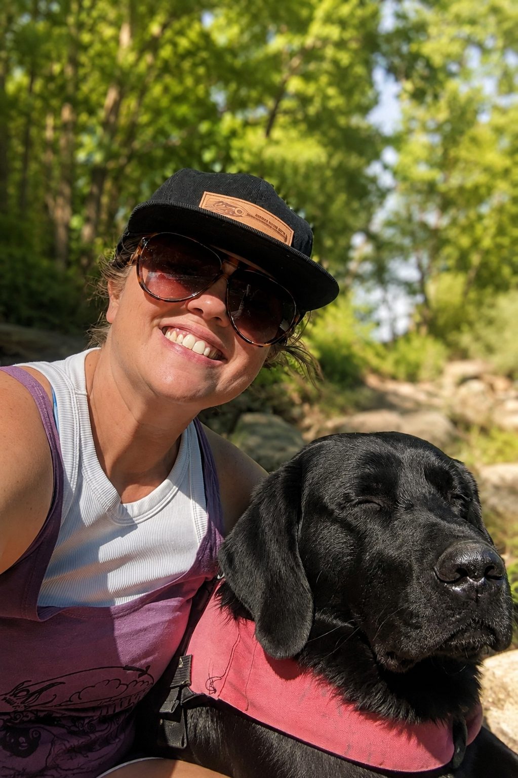 Jodie Miller outdoors on a trail with one of her black labs